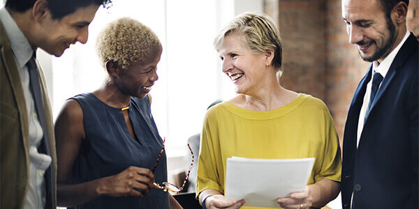 Group of people standing around each other staring at paper
